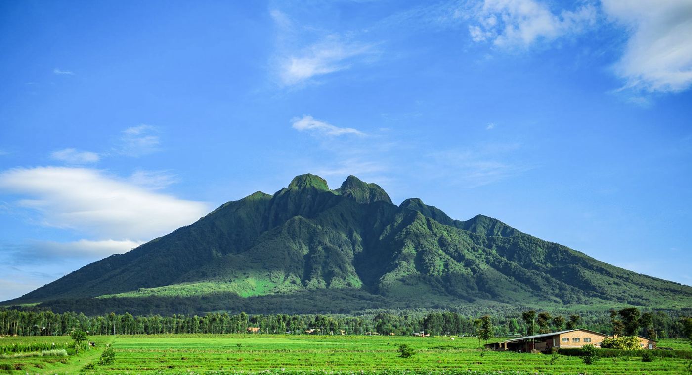 A green volcanic mountain under blue sky